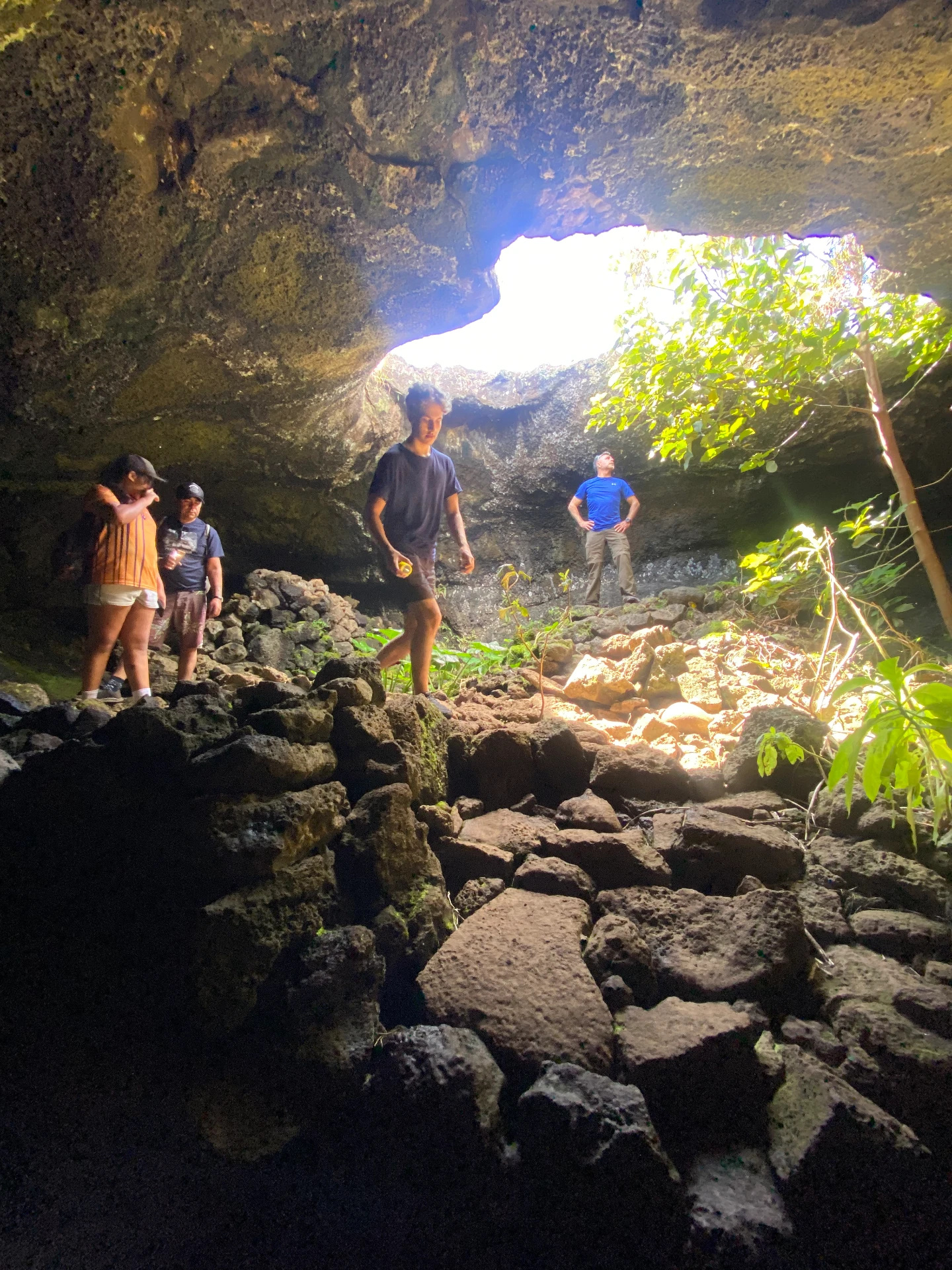 Visitors exploring a lava cave on Rapa Nui with daylight coming through an opening in the roof